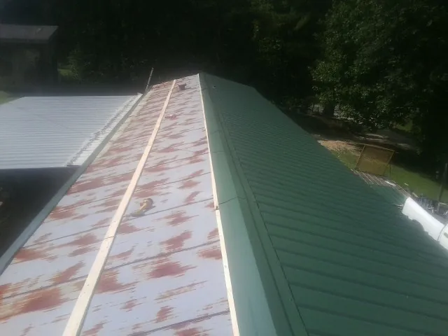 Old rusted panels beside newly installed green metal roofing — Wind Damage Roof Repair by Roofing Brothers in Elm Grove