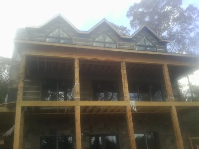 Dormers and porch framing on a large log home under construction — Roof Coating work by our crew in Elm Grove