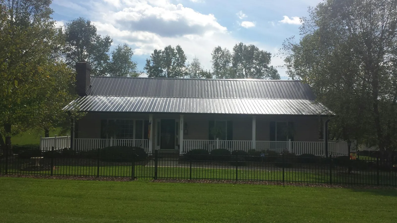 Gray metal roof on a brick ranch with a full width front porch — Gutter Guard Installation work by our crew in Elm Grove
