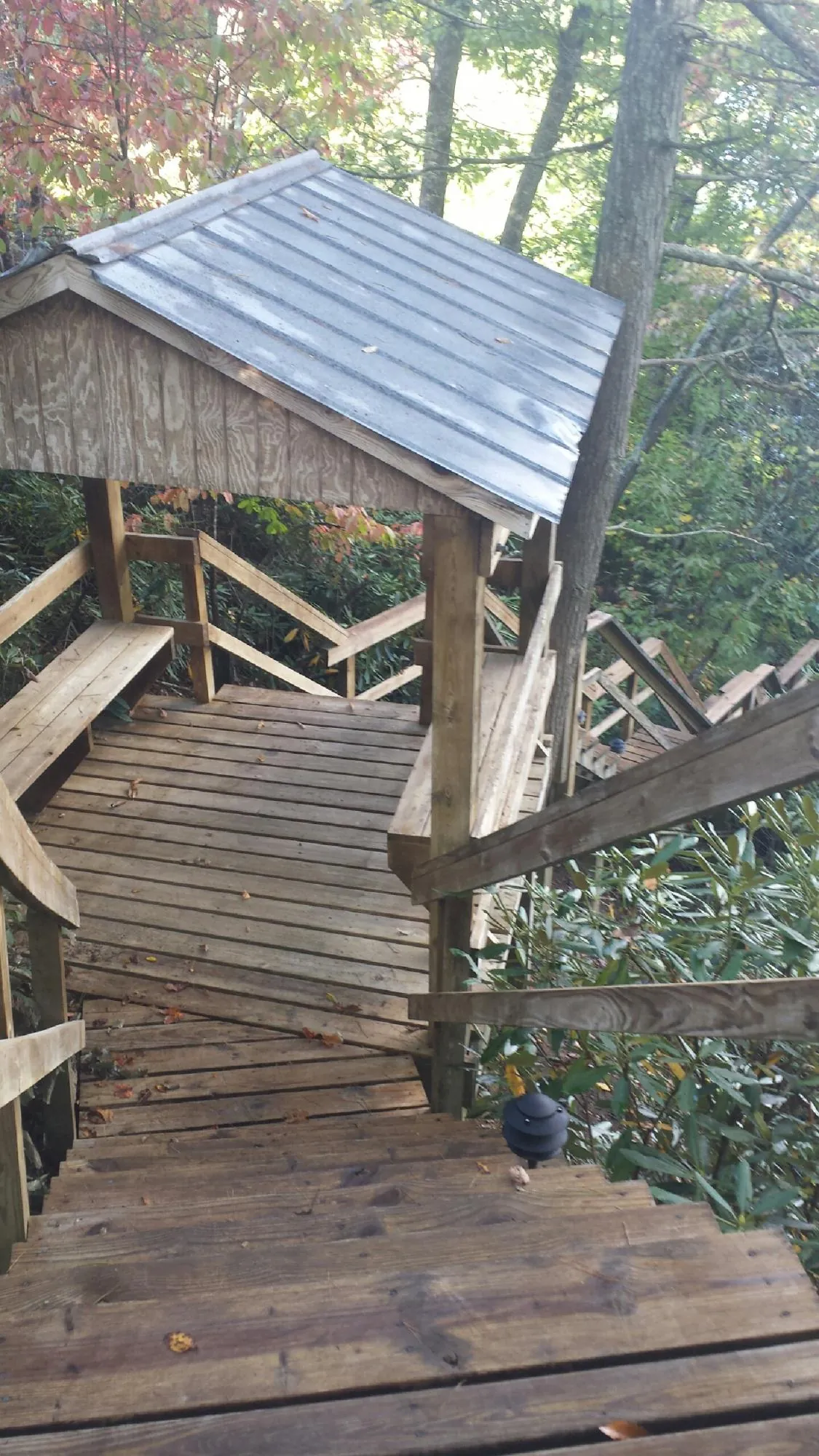 Metal roofed shelter over wooden steps on a wooded walkway — Skylight Repair & Installation work by our crew in Elm Grove