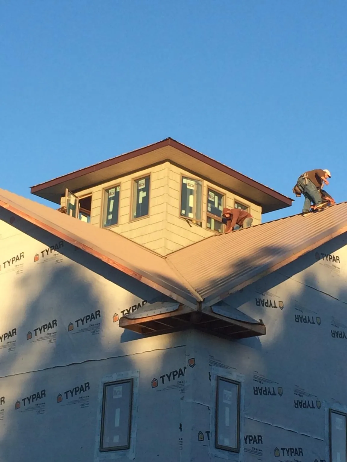 Roofers working around a rooftop cupola on a new metal roof at sunset — Roof Waterproofing in Elm Grove by Roofing Brothers